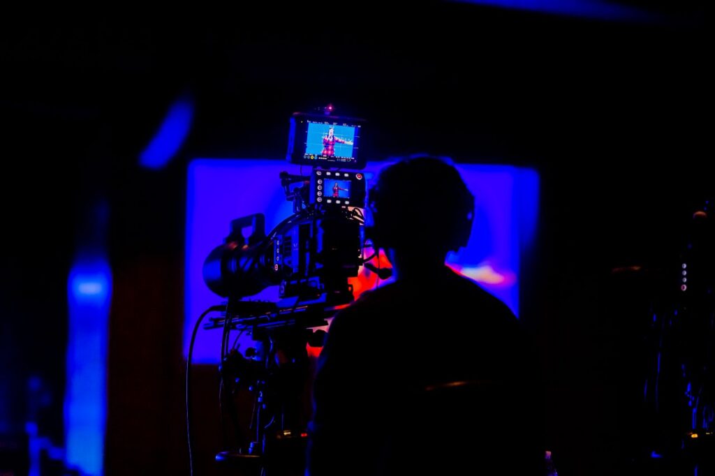 Cameraman capturing footage in low light during night event with vivid colors.